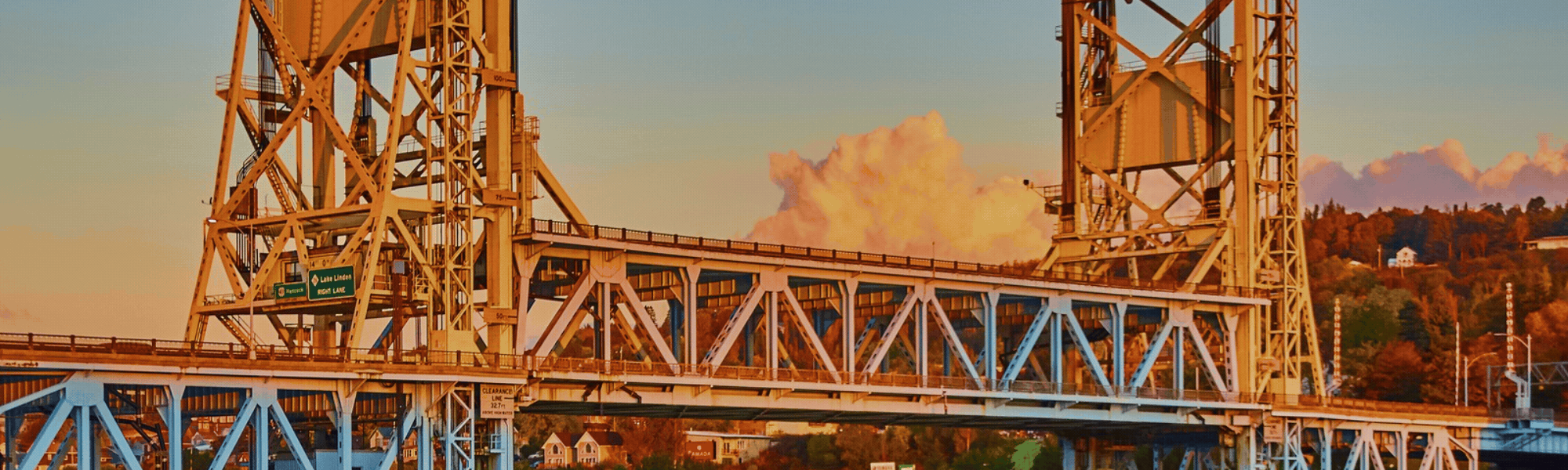 Panoramic view of the Portage Lake Lift Bridge connecting Houghton and Hancock, Michigan, reflected in calm water at sunrise in the Keweenaw Peninsula of Michigan's Upper Peninsula.